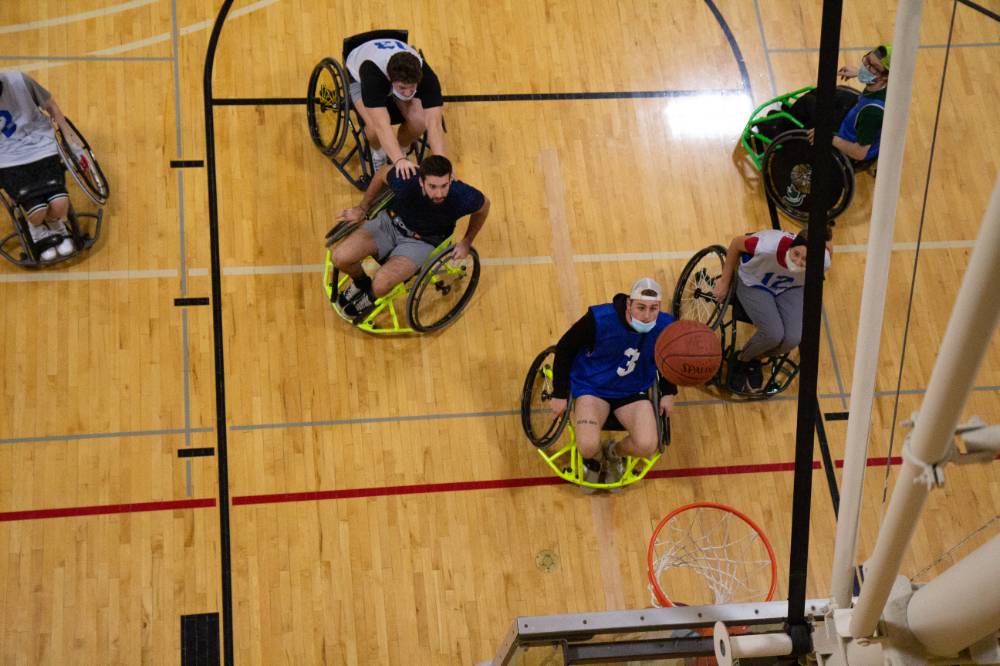 Adults in wheelchairs watching basketball in the air.